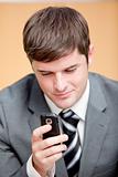 Self-assured businessman writing a text message with his mobile 