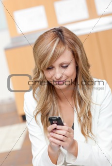 Concentrated businesswoman sending a text message with her cellp