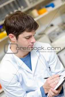 Concentrated scientist writing on a clipboard