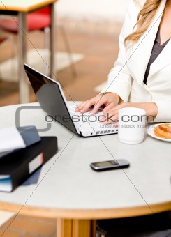 Close-up of a busy businesswoman using her laptop with cellphone