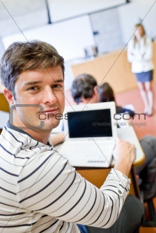 Close-up of a bright male student using a laptop during a university lesson