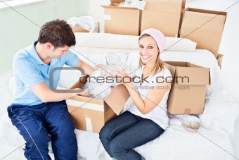 Concentrated young couple unpacking boxes with glasses