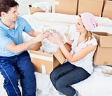 Affectionate young couple unpacking boxes with glasses
