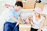 Positive young couple unpacking boxes with glasses