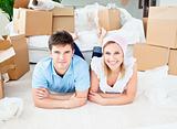 Smiling couple lying on the floor after unpacking boxes