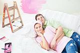 Delighted couple lying on the sofa after painting their new room