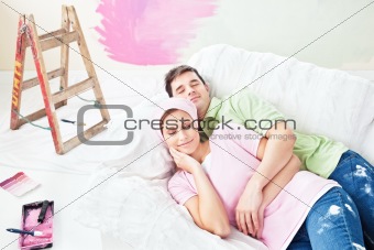 Delighted couple lying on the sofa after painting their new room