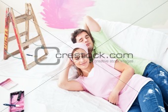 Relaxing couple lying on the sofa after painting their new room