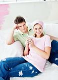 Delighted couple lying on the sofa and holding coffee after pain