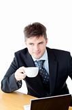 Attractive businessman holding a cup of coffee in front of his l