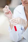 Close-up of a smiling scientist holding a pipette and a test tub