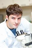 Handsome male scientist using a microscope