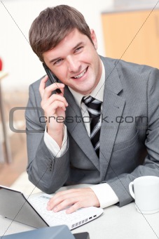 Charismatic businessman using his laptop while talking on phone