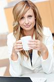 Bright businesswoman holding a cup of coffee in front of her lap