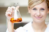 Close-up of a female scientist holding an erlenmeyer and smiling
