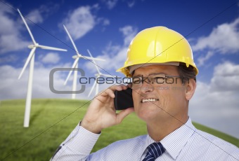 Hard Hat Wearing Engineer on Phone with Turbines Behind