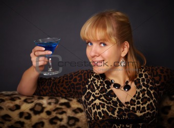 Beautiful young woman drinking blue cocktail