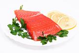 Salmon steak with lemon slices and parsley on white plate