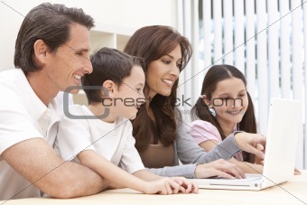Family Sitting Using Laptop Computer At Home