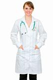 Smiling medical doctor woman holding hands in pockets of robe

