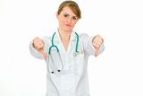 Displeased medical doctor woman showing thumbs down gesture
