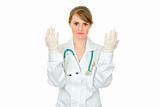 Concentrated  doctor woman holding up hands in latex medical gloves
