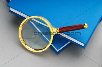 Magnifying glass over the stack of books 