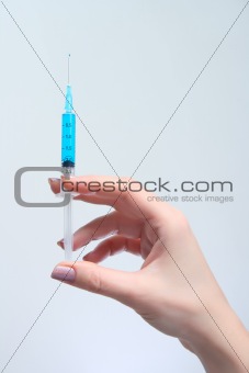Woman holds in her hand medical suringe with blue solution