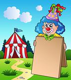 Clown holding board near tent