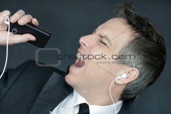 Businessman Wearing Headphones Sings Into Cell Phone