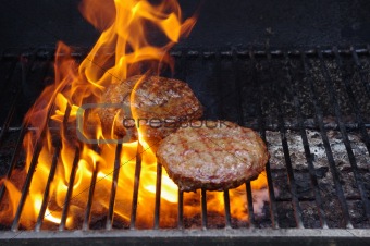 Hamburgers on a flaming BBQ
