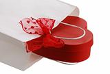 Closeup of white paper gift bag with red bow and heart shaped pr