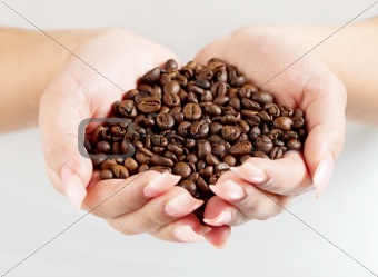 female hands cupped holding coffee beans
