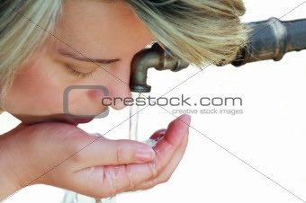 Beautiful blond young woman drinking water from tap