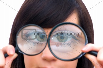 Girl's eye magnified through magnified glass on white