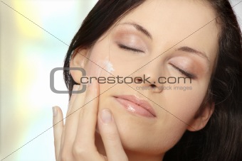 Beautiful young woman applying cream. 