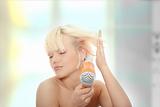 Young blonde woman using hair drier