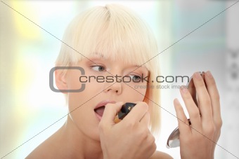 A beautiful young woman applying her make-up