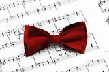 Red bow tie on musical notes paper