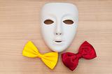 Masks and bow ties on the wooden background