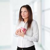 Young beautiful woman standing with piggy bank
