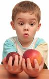 The child holds two different fruit in hands