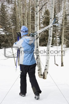 Female walking with skis.