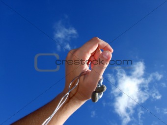 Hand with small headphones on a background of the blue sky