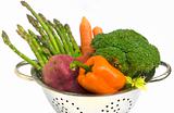 Fresh vegetables with water drops in colander on white isolated