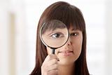 Businesswoman looking into a magniying glass