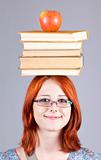 Red-haired girl keep apple and books on her head.