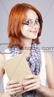 Red-haired girl keep book in hand. Studio shot.