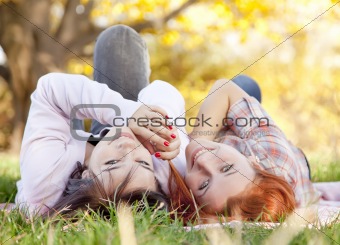 Two beautiful girlfriends at the autumn park near tree. 