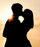 Couple kissing in sunrise at the beach.